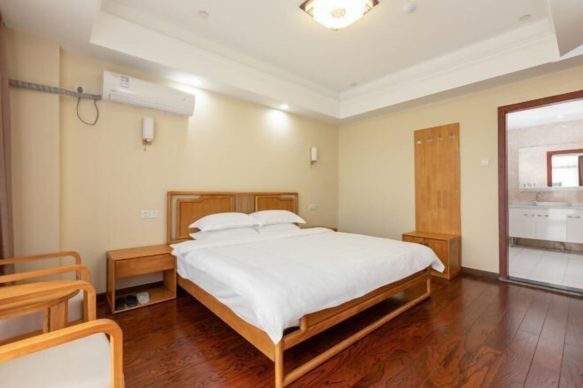 Une chambre à coucher avec un lit en bois, des tables de chevet, une armoire et un appareil de climatisation.
