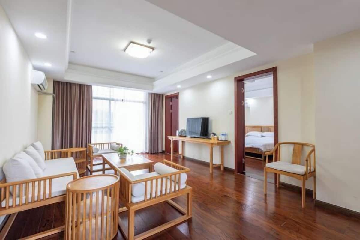 Una habitación de hotel con un sofá de madera, una mesita con un televisor, una cama y una silla.