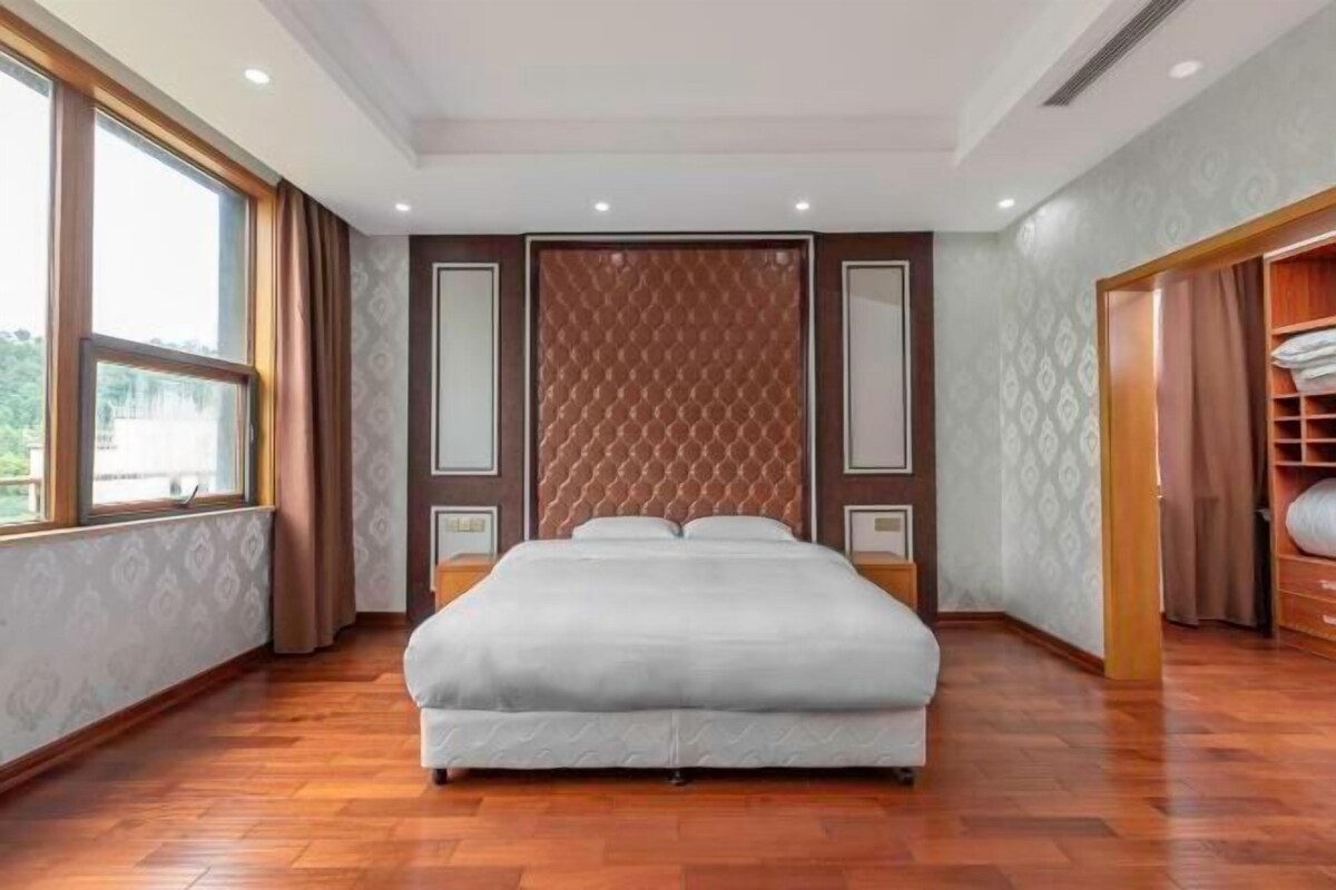 Une chambre d’hôtel avec un grand lit, un plancher en bois, une fenêtre et une armoire.