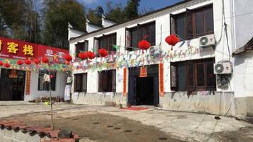 Un edificio con varias ventanas, un letrero rojo y farolillos rojos.