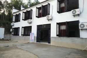 Un edificio con varias ventanas de marco negro, unidades de aire acondicionado y un cartel.