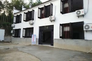 Un edificio con varias ventanas de marco negro, unidades de aire acondicionado y un cartel.