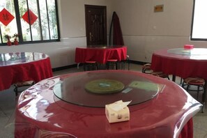A room with round tables covered in red tablecloths, chairs around them, and a window with red decorations. - Yinxingshu Inn (Jing County)
