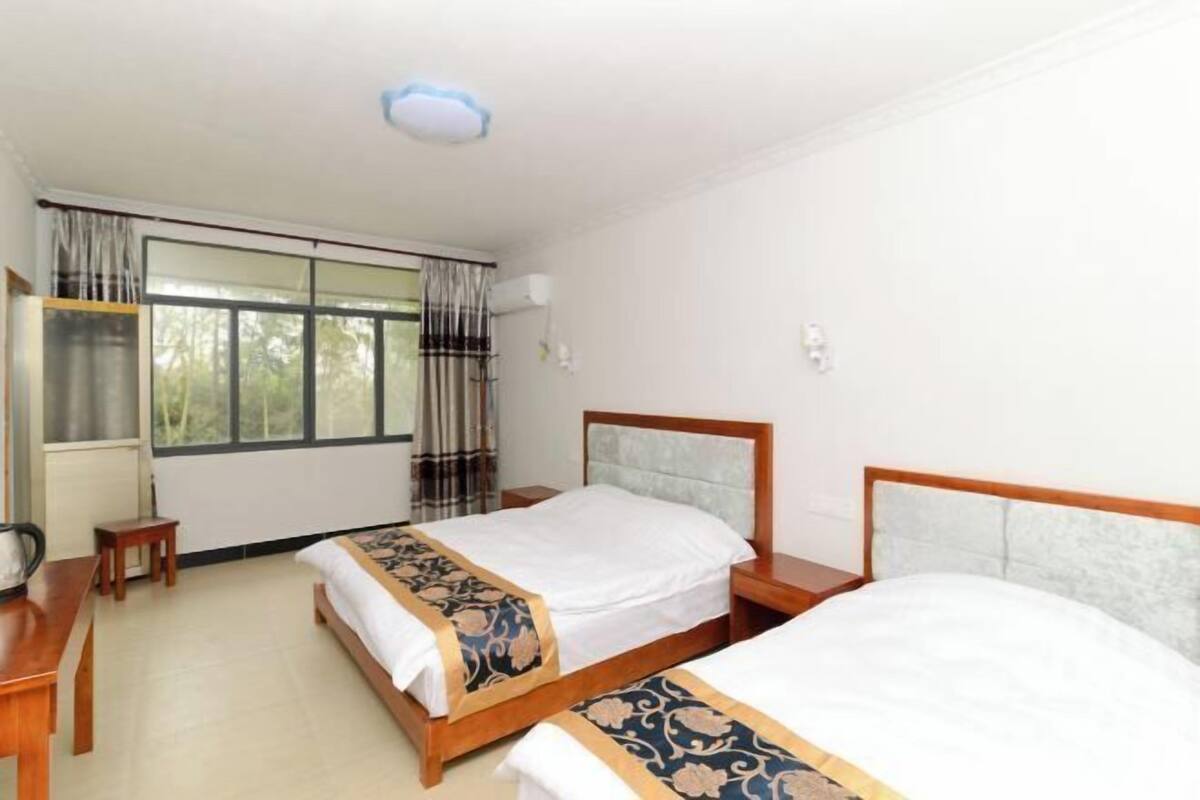 A hotel room with two beds, a desk, and a window with curtains.