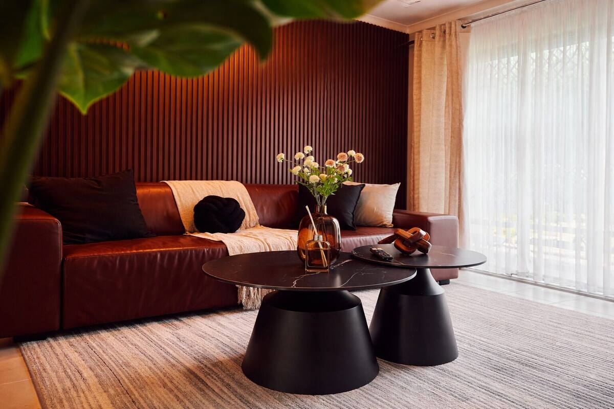 Uma sala de estar moderna com um sofá de couro, uma mesa de centro de vidro e um vaso com flores.