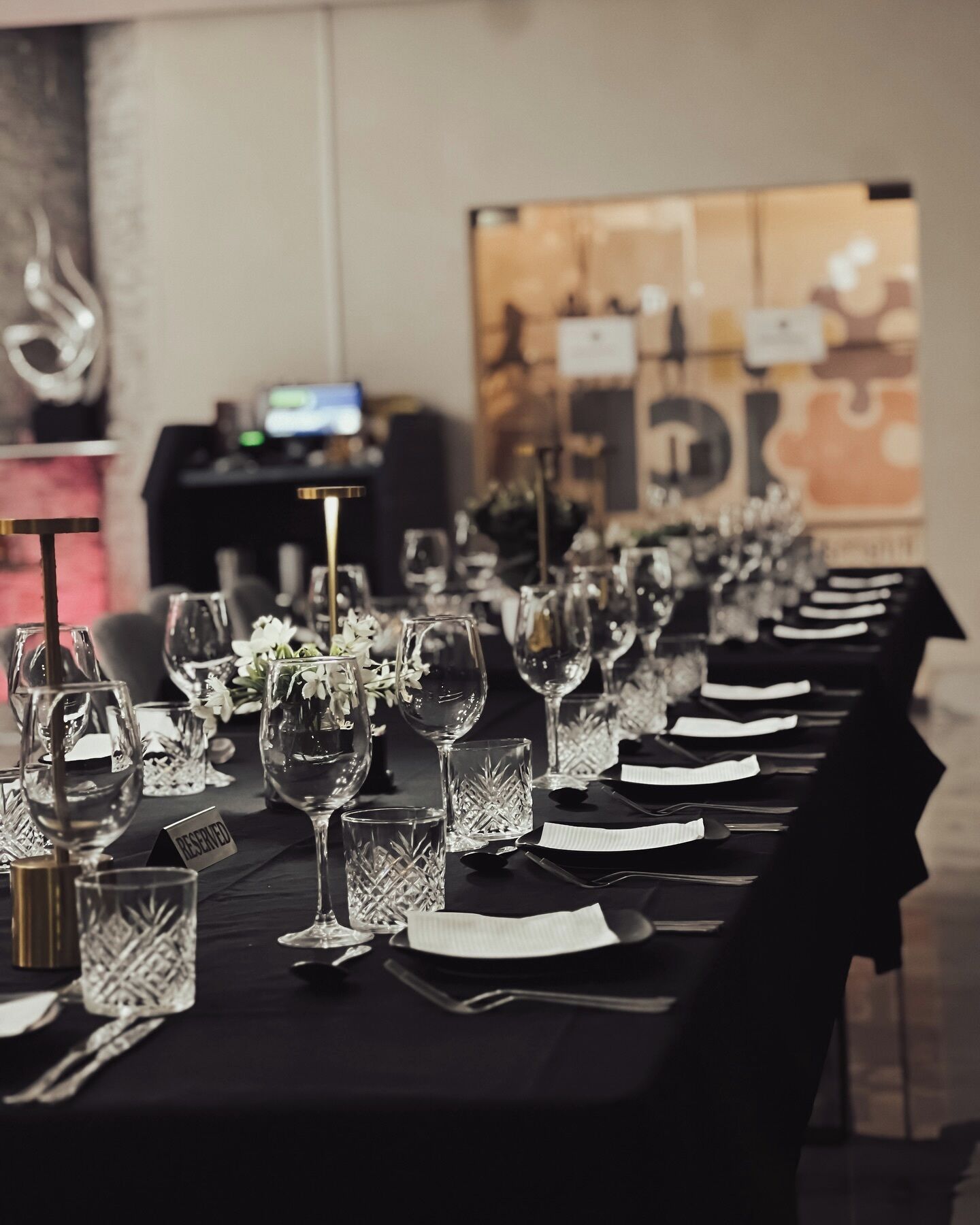 A long table set for a formal event with multiple wine glasses, water glasses, and cutlery.
