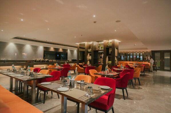 A modern restaurant with multiple dining areas, including a bar and a private dining section.