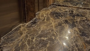 Zona de ascensores con suelo de mármol y puertas metálicas.