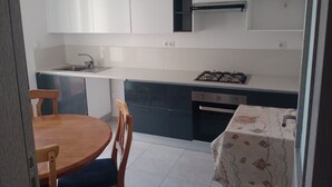 Una cocina compacta con comedor, que incluye un lavamanos, estufa y alacenas.