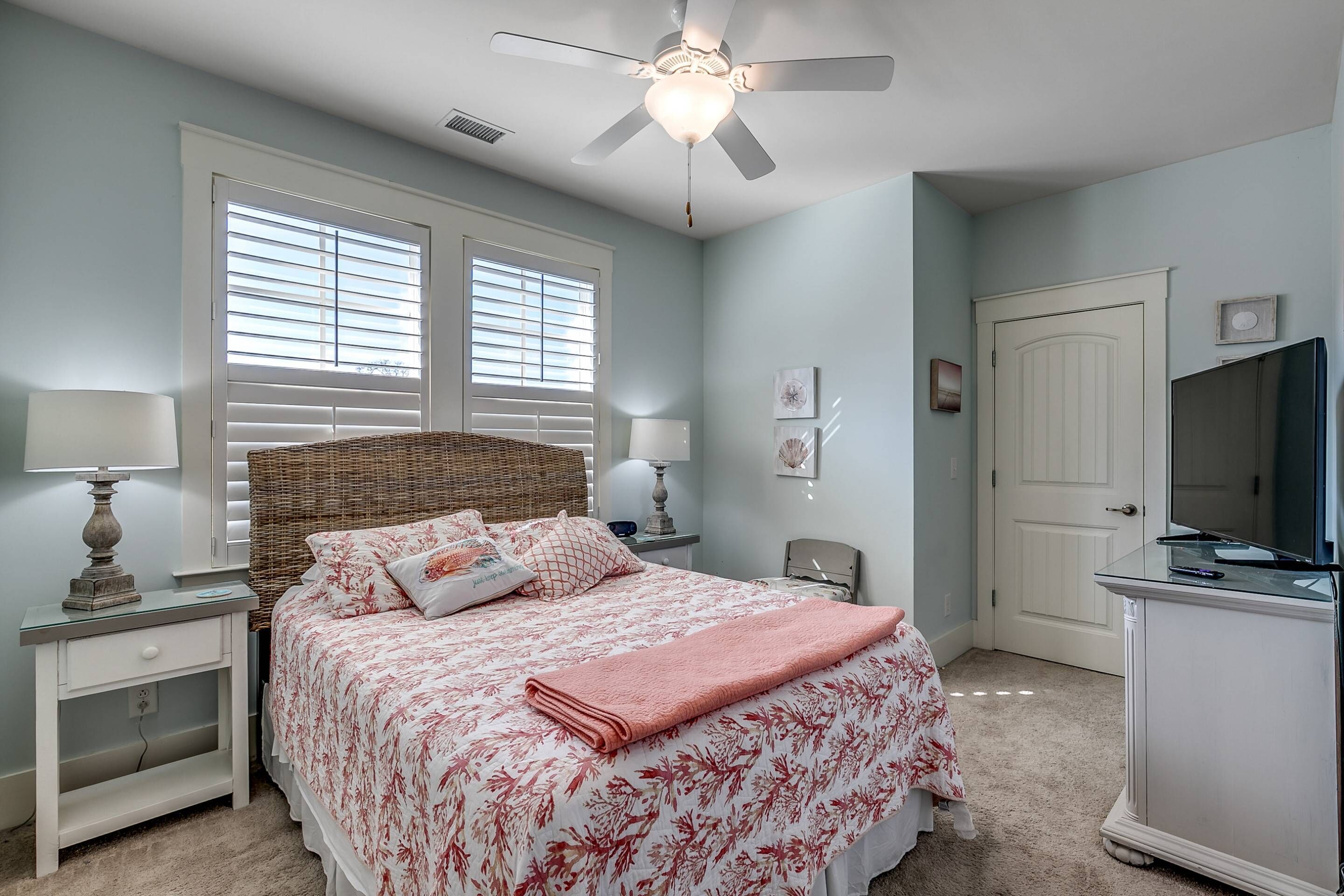 A bedroom with a bed, nightstands, a dresser, a ceiling fan, and a television.