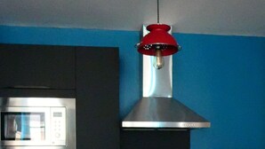 Una cocina con microondas, un refrigerador rojo y una lámpara colgante.