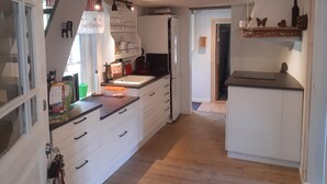 Eine Küche mit weißen Schränken, Holzboden und einem Fenster mit Vorhängen.