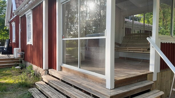 Eine Holzterrasse mit einer Glastür zu einem überdachten Außenbereich.