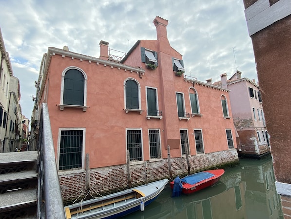 A pink building with arched windows and a canal.