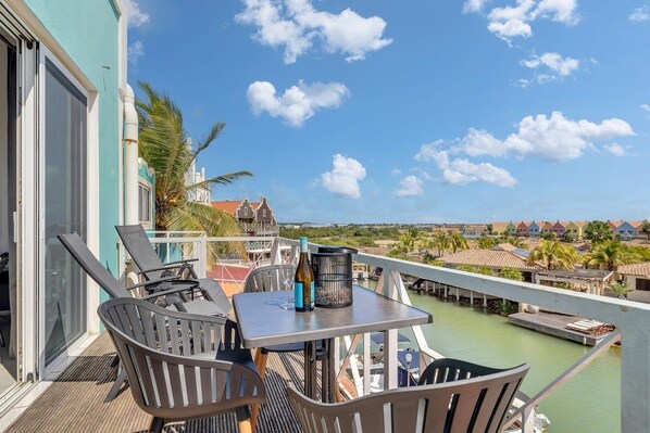 A balcony with a table, chairs, and a bottle.