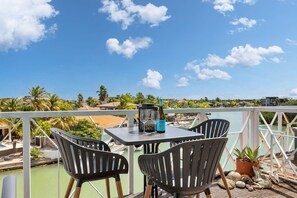 Ein Balkon mit Tisch, Stühlen und einer Flasche Alkohol.