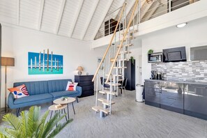 Un intérieur moderne comprenant un escalier, un canapé, un coin repas et une cuisine.
