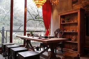 Un comedor con mesa de madera, bancos y una estantería.