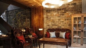 Une pièce rustique avec une table basse en bois, un canapé avec des coussins rouges, un meuble en bois et un escalier.