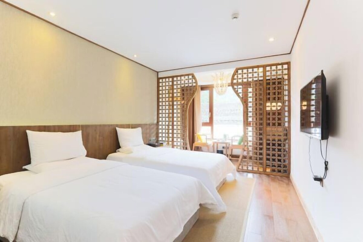 Une chambre d’hôtel avec deux lits, un téléviseur fixé au mur et une cloison en bois.