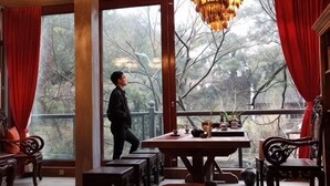 Une pièce dotée d’une grande table, de bancs et offrant une vue sur l’extérieur grâce à de larges fenêtres.
