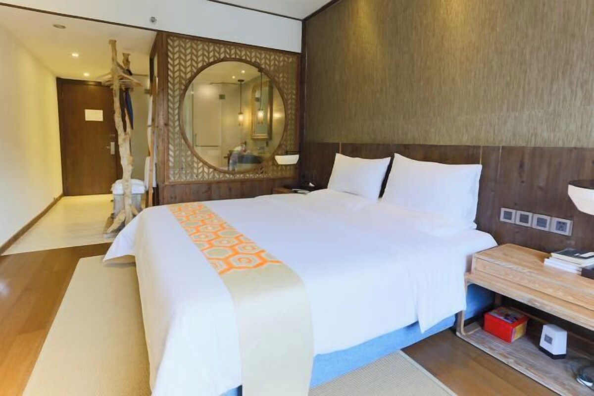 Une chambre d’hôtel avec un grand lit, une tête de lit en bois, une table de chevet avec une lampe et un miroir.