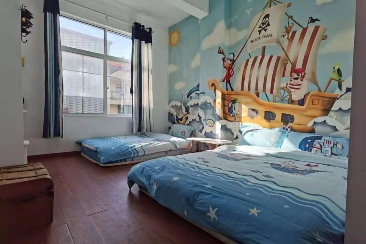 Una habitación con dos camas, un ventanal grande y un mural de un barco pirata.