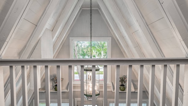 Una habitación con techos altos y un techo inclinado, un farol colgante y una ventana con vistas a la vegetación.