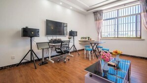 Um escritório moderno com uma mesa grande, computador, alto-falantes, uma televisão na parede e uma janela com cortinas.