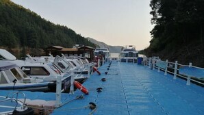 A dock with several boats moored in a row, a wooden structure on the left, and a white fence on the right. - Ningguo Julongwan Farmstay (Ningguo)