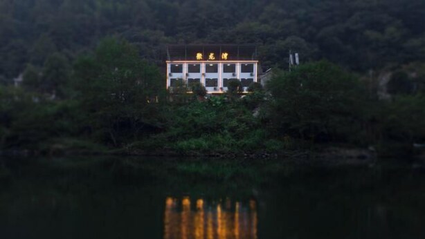 A building with a reflection in the water, surrounded by greenery. - Ningguo Julongwan Farmstay (Ningguo)