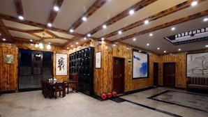 Un intérieur en bois comprenant un coin repas, une étagère noire et des œuvres d’art accrochées aux murs.