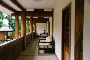 A corridor with wooden beams, a bench, and a view of a traditional building.