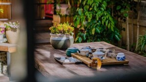 Une table en bois, sur laquelle est disposée une vaisselle à thé comprenant des tasses, une théière et un plateau, dans un espace intérieur accueillant et agrémenté de plantes.