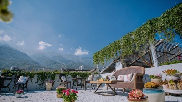 Une terrasse avec des sièges d’extérieur, un canapé en osier et des plantes en pot.