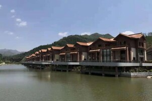Una hilera de edificios de estilo tradicional con una masa de agua al frente y montañas al fondo.
