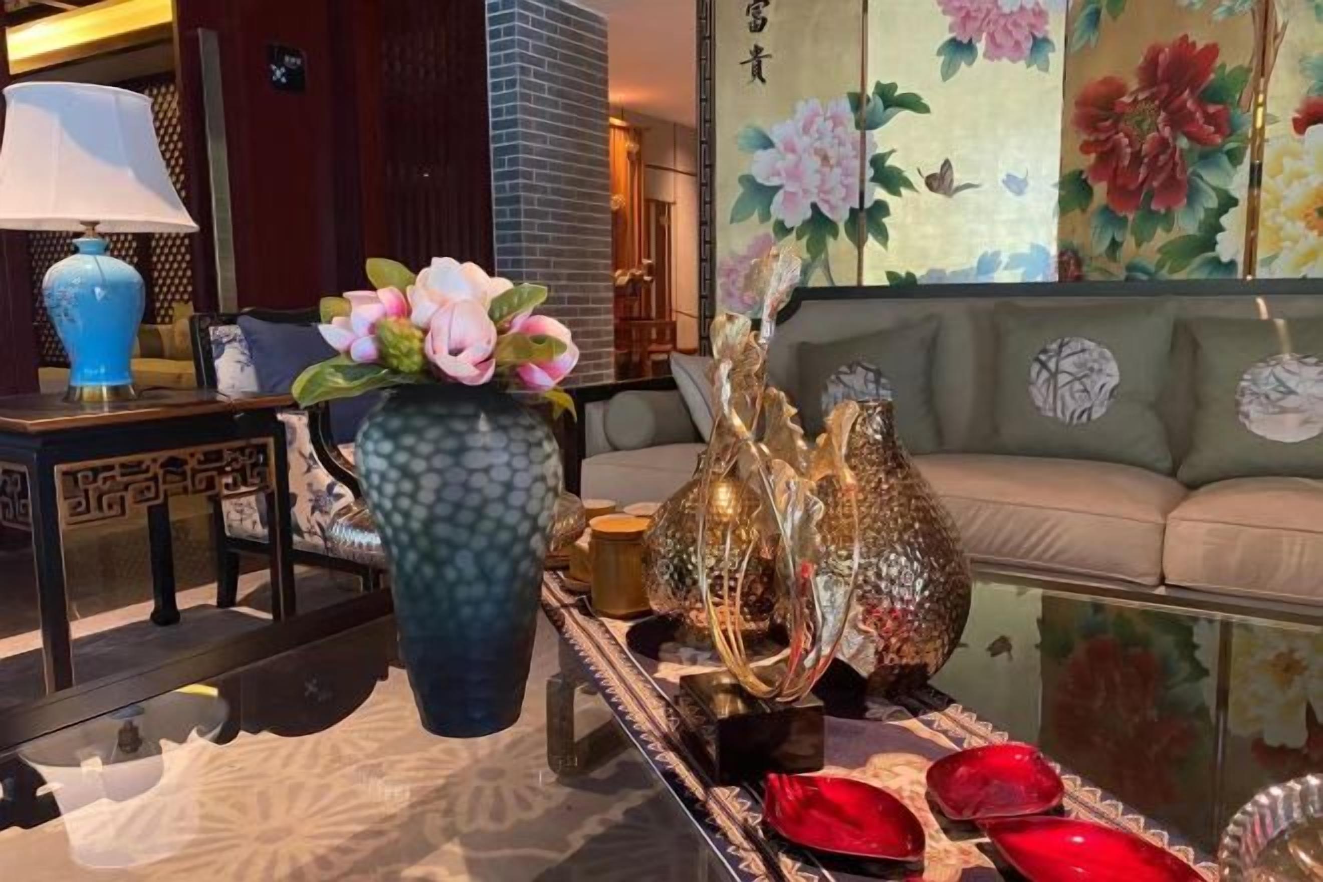 A room with a sofa, a table with decorative items, and a vase with flowers.