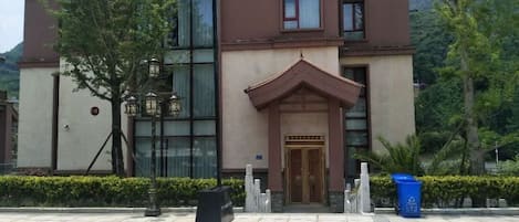 A modern building with a traditional entrance, large windows, and a well-maintained garden area.