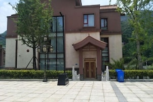A modern building with a traditional entrance, large windows, and a well-maintained garden area.