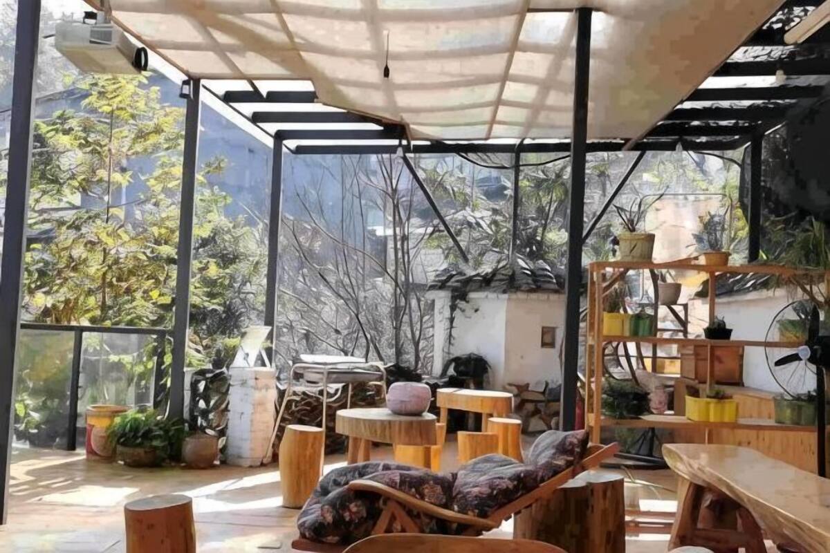 An outdoor patio with wooden furniture, a covered seating area, and potted plants.