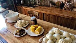 Ein Holztisch mit verschiedenen Gerichten, darunter Knödel, Maiskolben und eine Schüssel Suppe.