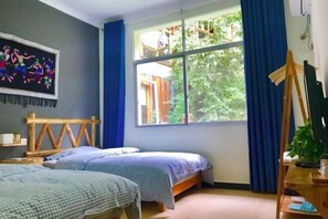 A room with two beds, a large window with blue curtains, a wooden headboard, and a painting on the wall. - Meet Cat Inn (Zhangjiajie)