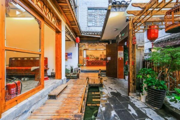 A narrow alleyway with wooden benches, a small water feature, and potted plants. - Zhen'Gan Club (Fenghuang County)