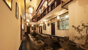 A corridor with a wooden bench, potted plants, and a staircase leading to an upper level. - Zhen'Gan Club (Fenghuang County)