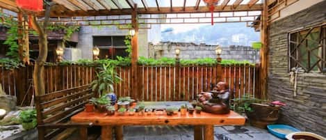 An outdoor patio with a wooden table, red lanterns, and potted plants.