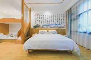 A bedroom with a bunk bed, a large bed with white bedding, a mural with Chinese calligraphy, and a view of the outdoors through a window. - Zhen'Gan Club (Fenghuang County)