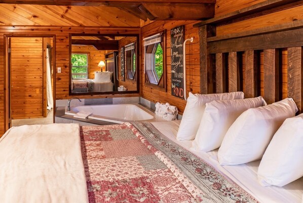 A wooden cabin bedroom with a bed, a large mirror, a window, and a wall with motivational quotes. - Mountain Ecstasy - Romantic Cabin w/ Beautiful View (Ponca)