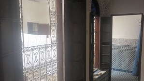 Un couloir intérieur agrémenté de grilles en métal ouvragées, d’un sol carrelé aux motifs décoratifs et de décorations murales élaborées.