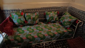 Un canapé d’angle recouvert d’un tissu à motifs, un sol à carreaux et un mur orné d’un motif.