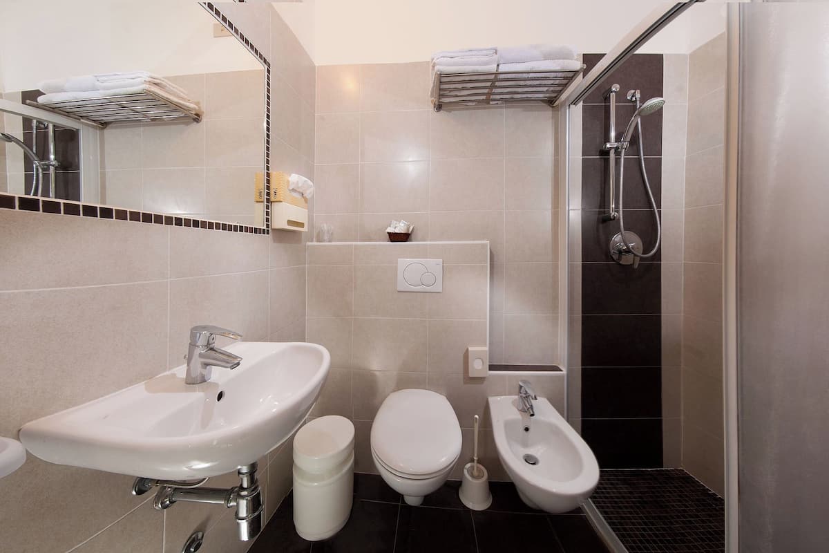 A modern bathroom with a sink, toilet, bidet, and shower.